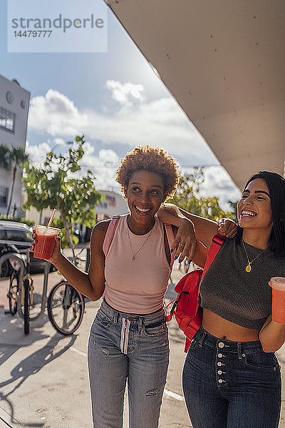 USA  Florida  Miami Beach  zwei glückliche Freundinnen bei einem Erfrischungsgetränk in der Stadt