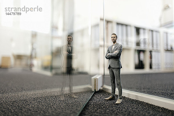 Geschäftsmann-Figur vor Glaswand im Büro stehend