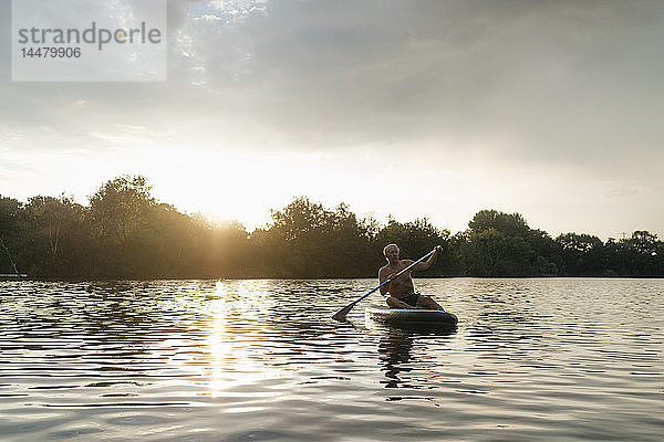 Älterer Mann im SUP-Vorstand bei Sonnenuntergang