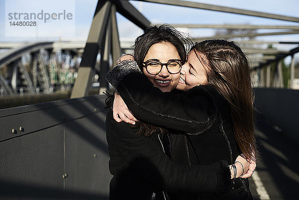 Glückliche Freunde  die sich auf einer Brücke umarmen