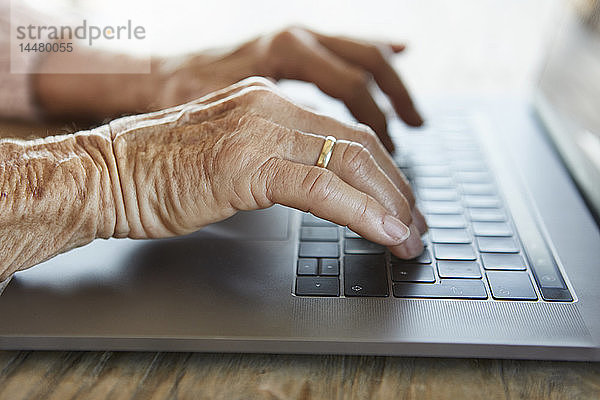 Hand einer älteren Frau beim Tippen auf der Tastatur eines Laptops  Nahaufnahme