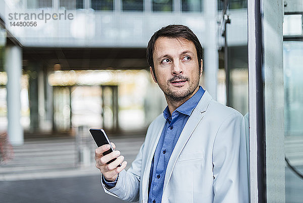 Porträt eines Geschäftsmannes mit Smartphone in der Stadt