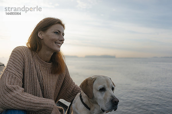 Deutschland  Hamburg  lächelnde Frau mit Hund am Elbufer