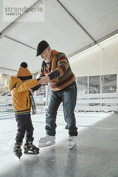 Grossvater und Enkel auf der Eisbahn  Schlittschuhlaufen