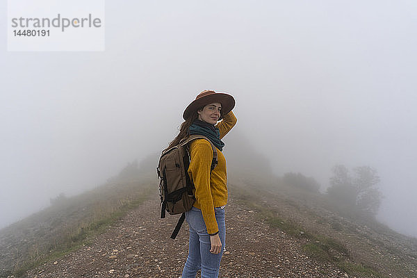 Frau  die im Nebel wandert und auf einem Bergpfad steht