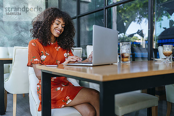 Porträt einer entspannten jungen Frau in einem Café mit Laptop