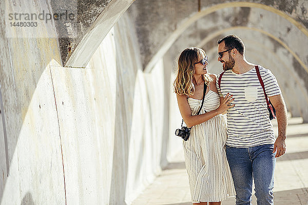 Spanien  Andalusien  Malaga  glückliches Touristenpaar beim Spaziergang unter einem Torbogen in der Stadt