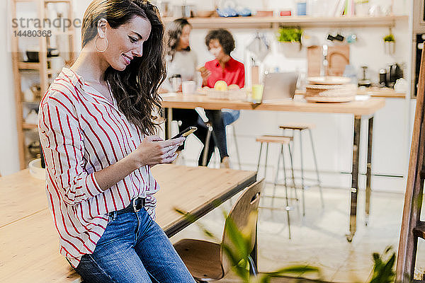 Lächelnde Frau mit Handy am Tisch