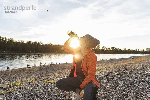 Sportliche Frau macht Pause am Fluss  Trinkwasser