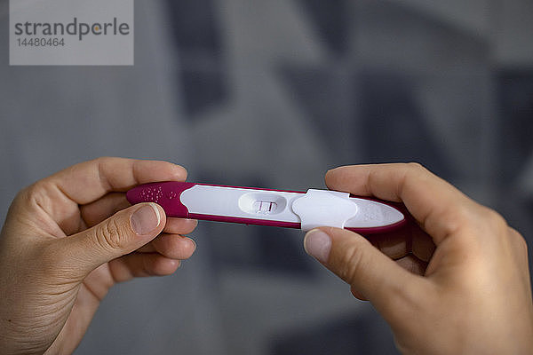 Nahaufnahme der Hände der Frau mit positivem Schwangerschaftstest
