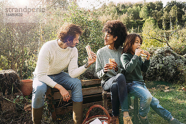 Glückliche Familie im Garten sitzen  eine Pause machen  Sandwiches essen