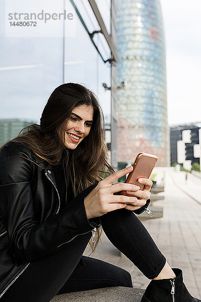 Spanien Barcelona  lächelnde junge Frau mit Handy in der Stadt