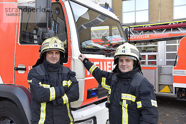 Porträt von zwei selbstbewussten Feuerwehrleuten vor dem Feuerwehrauto