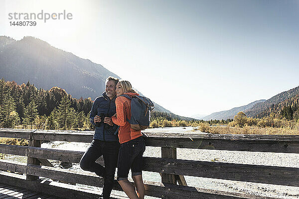 Österreich  Alpen  glückliches Paar auf einer Wanderung auf einer Brücke stehend