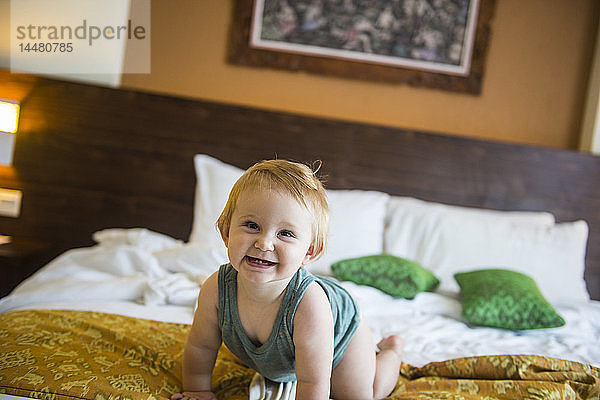 Kleines Mädchen auf Bett im Hotelzimmer