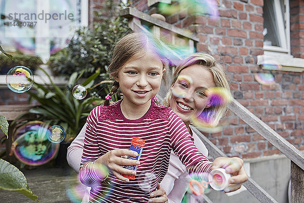 Glückliche Mutter und Tochter machen Seifenblasen