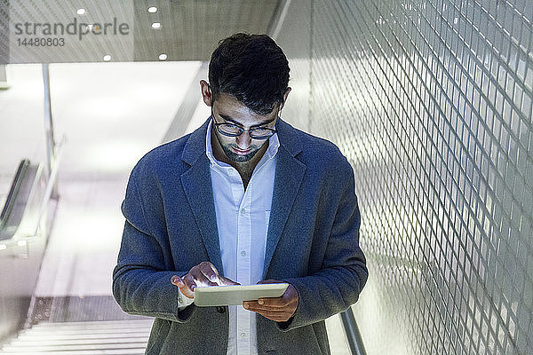Junger Geschäftsmann steht auf einer Treppe mit digitalem Tablett