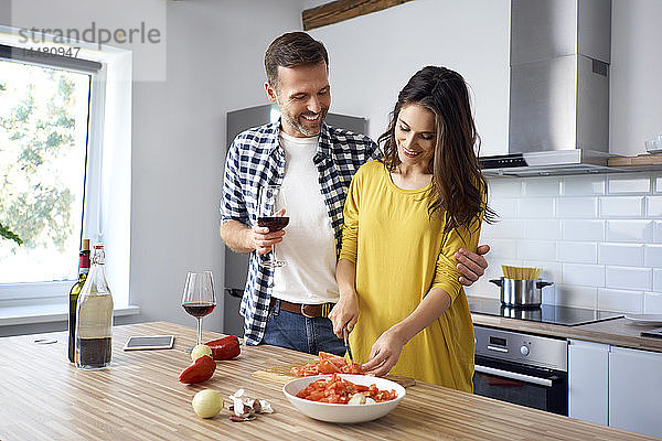 Liebespaar in der Küche  bereitet gemeinsam Spaghetti zu  trinkt Rotwein