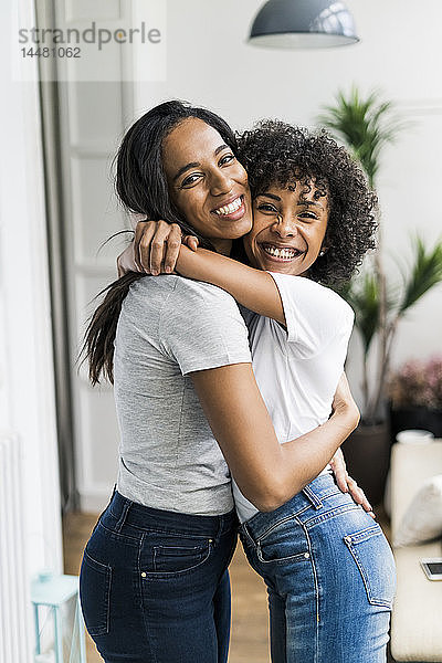 Porträt von zwei glücklichen Freundinnen  die sich zu Hause umarmen