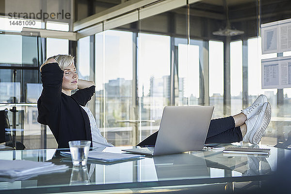 Geschäftsfrau  die mit geschlossenen Augen am Schreibtisch im Büro sitzt