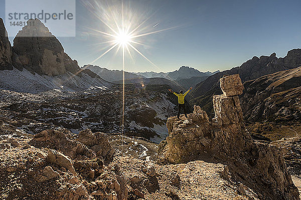 Italien  Tre Cime di Lavaredo  Mann wandert und schaut auf das Tal mit den Gipfeln und der Sonne über dem Horizont