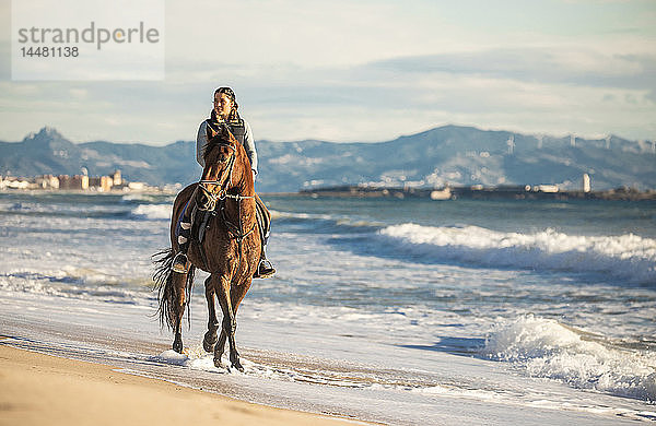 Spanien  Tarifa  Frau reitet Pferd am Strand