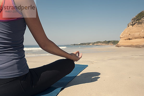 Nahaufnahme einer jungen Frau  die an einem Strand Yoga praktiziert