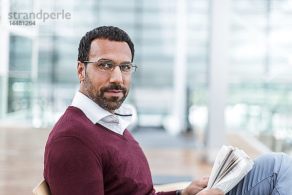 Geschäftsmann liest eine Zeitung im Wartesaal