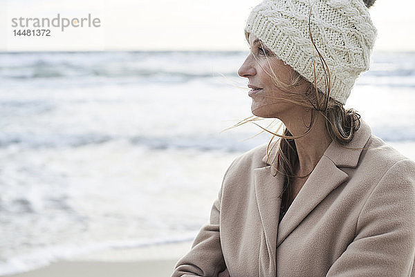 Spanien  Menorca  Profil einer älteren Frau mit Wollmütze am Strand im Winter