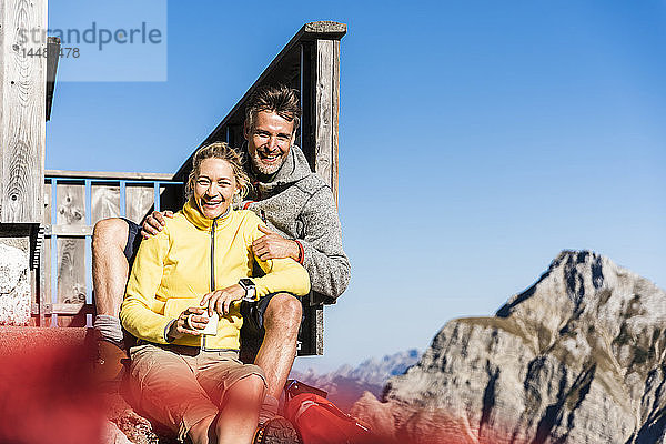 Wanderndes Ehepaar sitzt vor der Berghütte und macht eine Pause