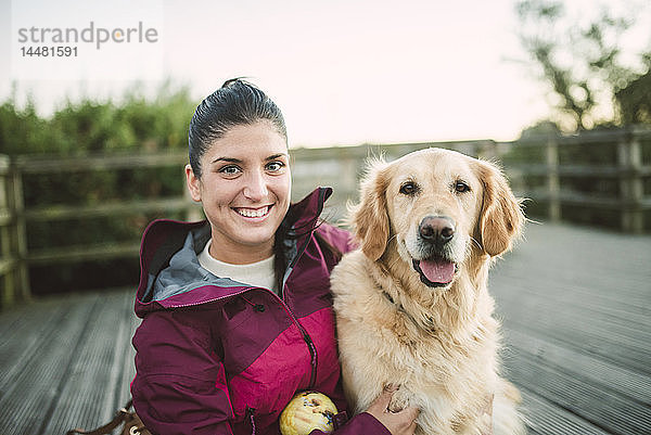 Porträt einer glücklichen jungen Frau mit ihrem Golden-Retriever-Hund im Freien