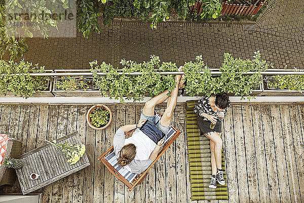 Junges Paar entspannt sich im Sommer auf ihrem Balkon  Mann benutzt Tablette