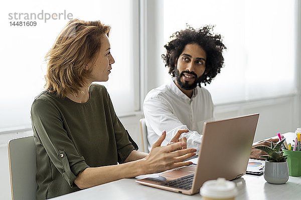 Junge Geschäftsleute im Coworking Space unterstützen sich gegenseitig