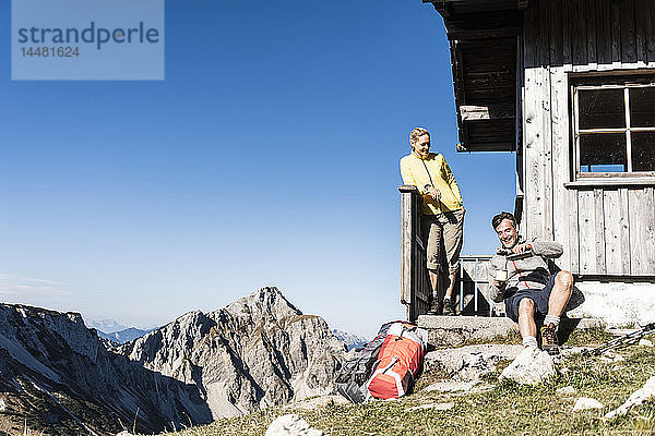 Wanderndes Ehepaar sitzt vor der Berghütte und macht eine Pause