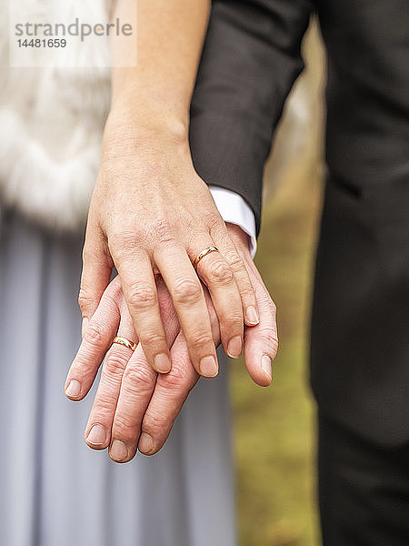 Nahaufnahme von Braut und Bräutigam beim Händchenhalten