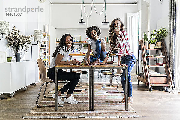 Porträt von drei glücklichen Frauen bei Tisch zu Hause