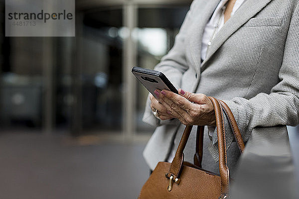 Nahaufnahme einer Geschäftsfrau mit Handy und Handtasche