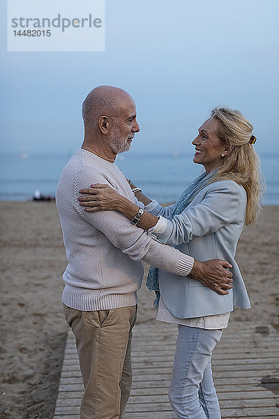 Spanien  Barcelona  glückliches älteres Paar umarmt sich in der Abenddämmerung am Strand