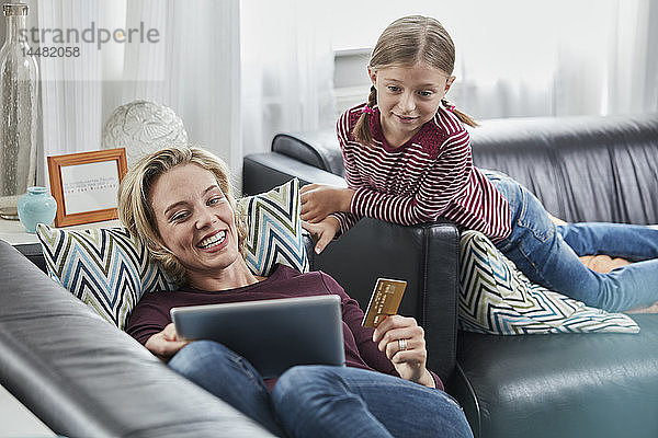 Glückliche Mutter und Tochter beim Online-Einkauf auf der Couch zu Hause