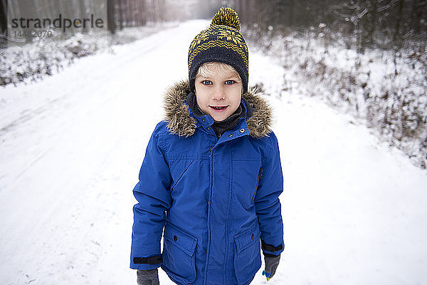 Porträt eines kleinen Jungen beim Spaziergang im Winterwald
