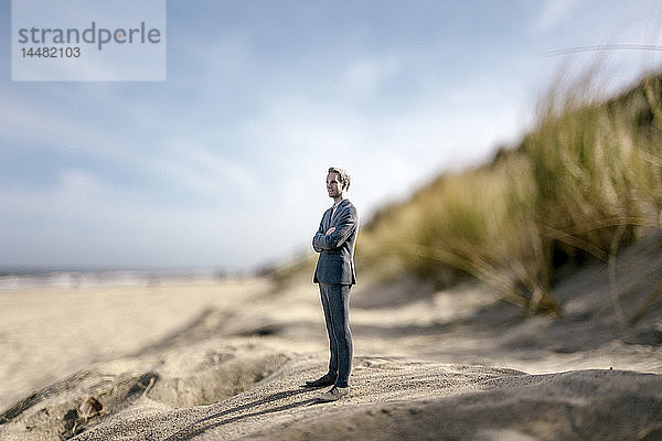 Geschäftsmann-Figur auf einer Sanddüne stehend  schaut in die Ferne