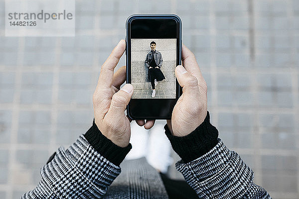 Mann hält Smartphone mit Foto von sich selbst in der Hand  Nahaufnahme