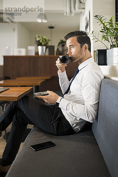 Geschäftsmann genießt Kaffee und macht eine Pause auf einer Bank im Café