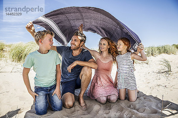 Niederlande  Zandvoort  glückliche Familie unter einer Decke am Strand