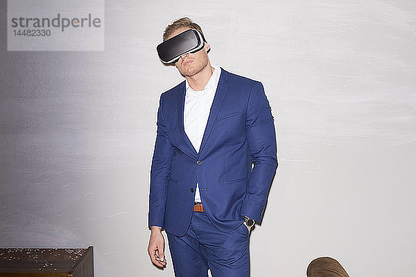 Junger Mann im blauen Anzug mit Virtual-Reality-Brille