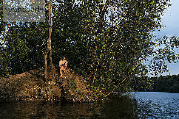 Mann sitzt auf einer Insel in einem See