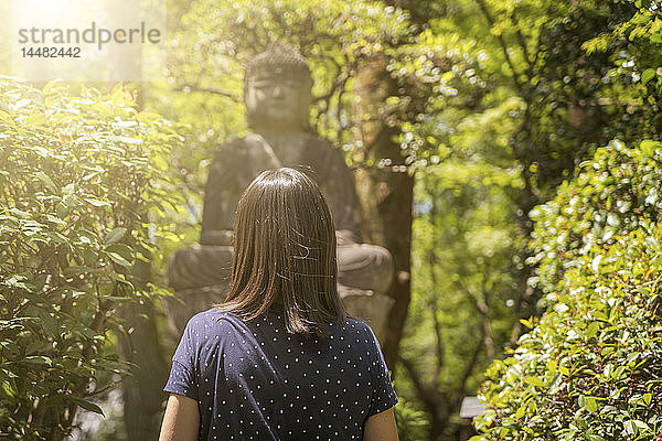 Frau betrachtet Buddhastatue an einem sonnigen Tag