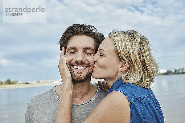 Glückliches junges Paar küsst sich am Strand