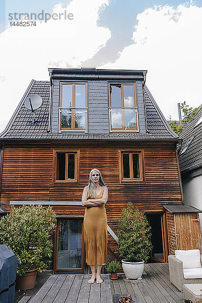 Frau steht auf der Terrasse ihres Hauses