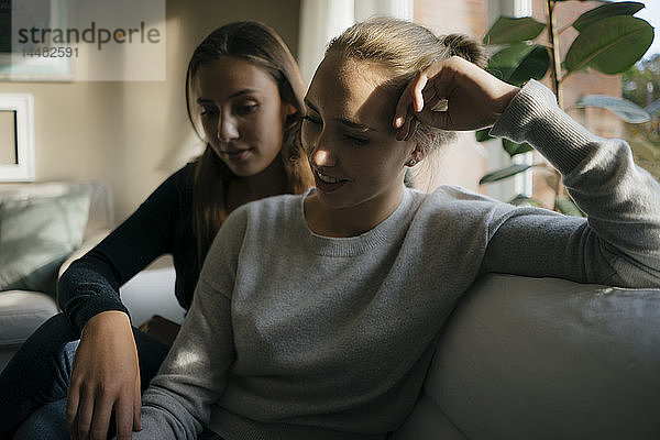 Zwei Teenager-Mädchen sitzen zu Hause auf der Couch